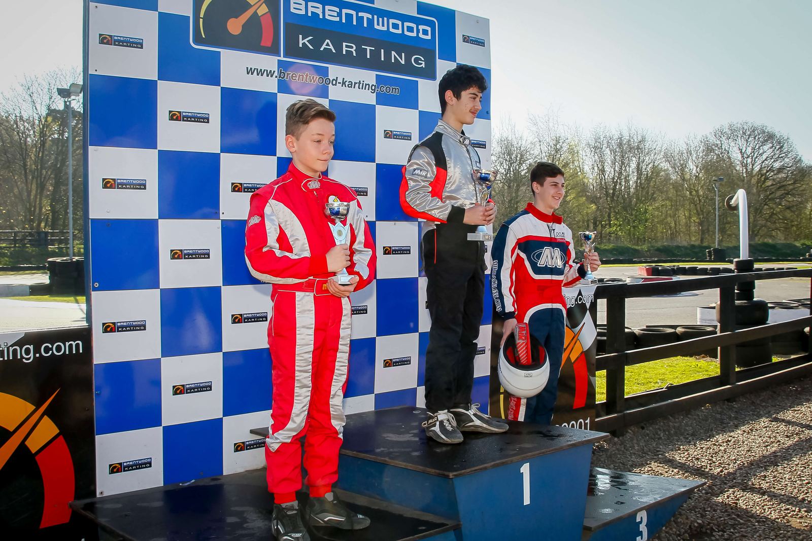 Three young drivers on the podium with trophies